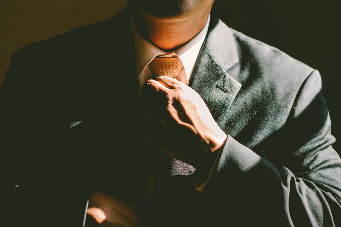 Photo of a man wearing a suit and loosening his tie. Photo by Ben Rosett on Unsplash.