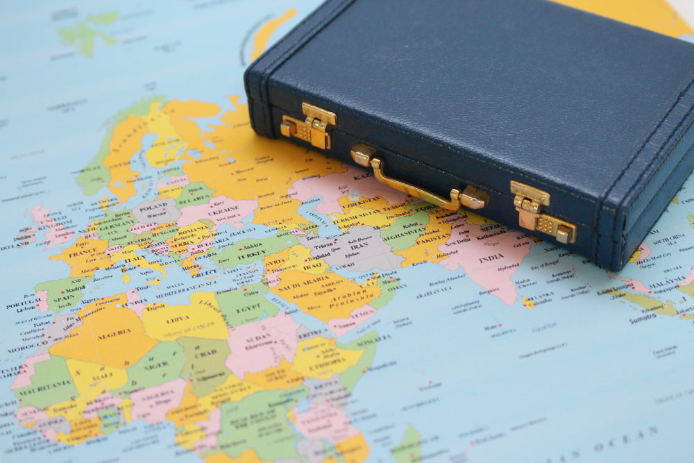 A black briefcase placed on a world map, symbolizing international business, global travel, or cross-border professional endeavors.