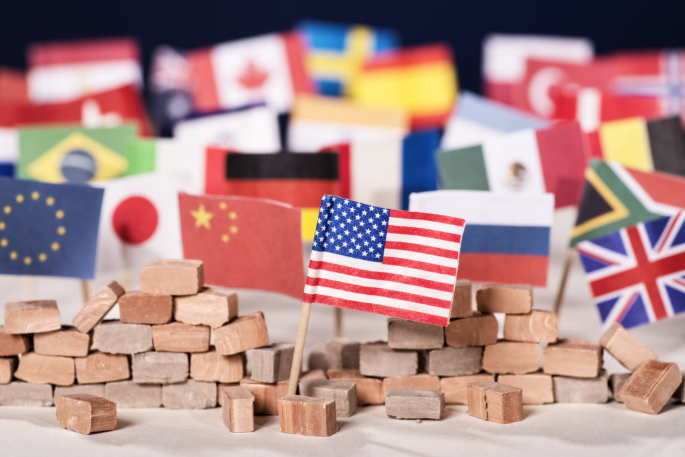 Miniature flags of various countries, including the US, China, and UK, placed among small bricks, symbolizing global relations or diplomacy.